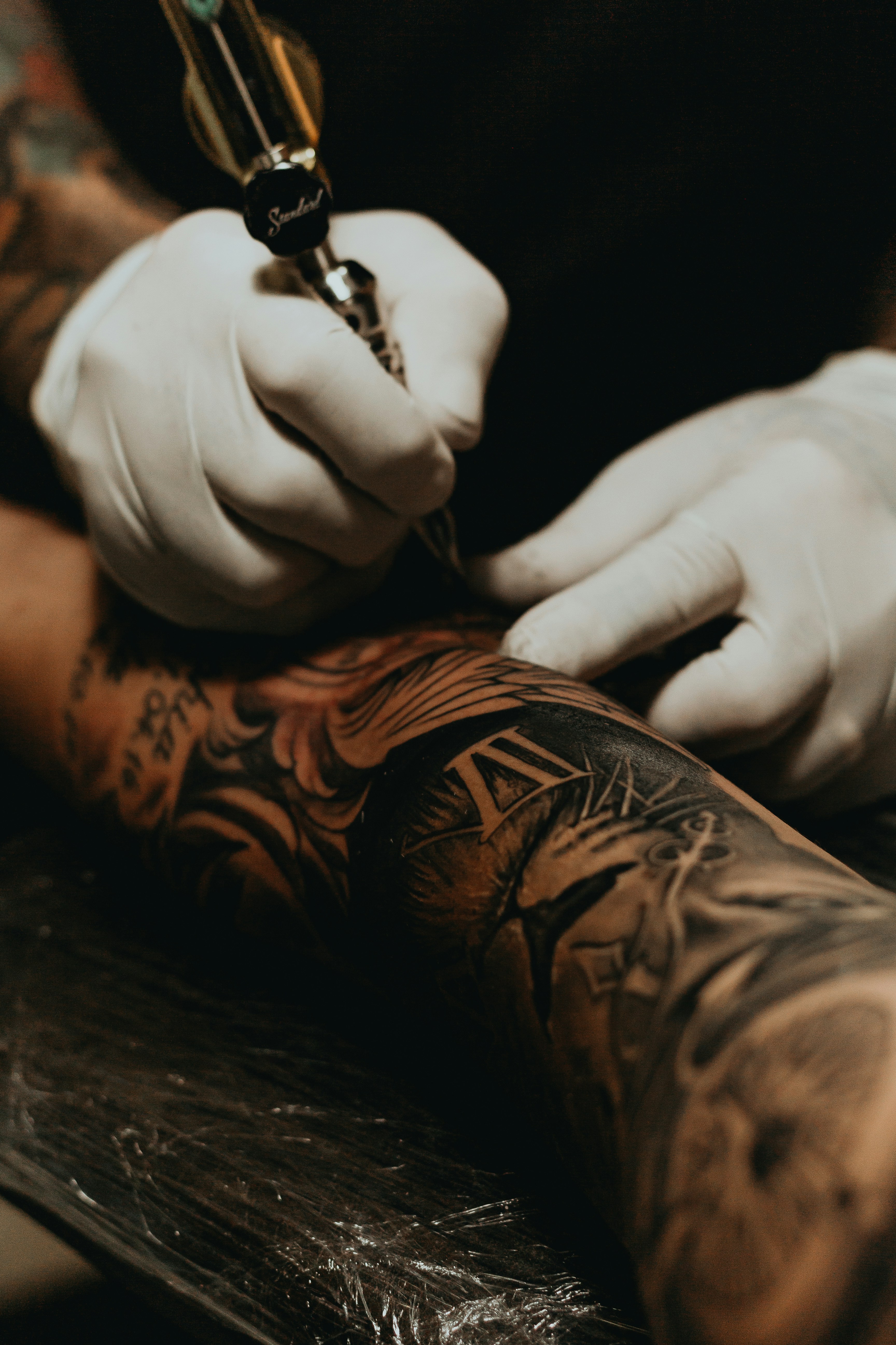 Tattoo artist working on a detailed sleeve tattoo