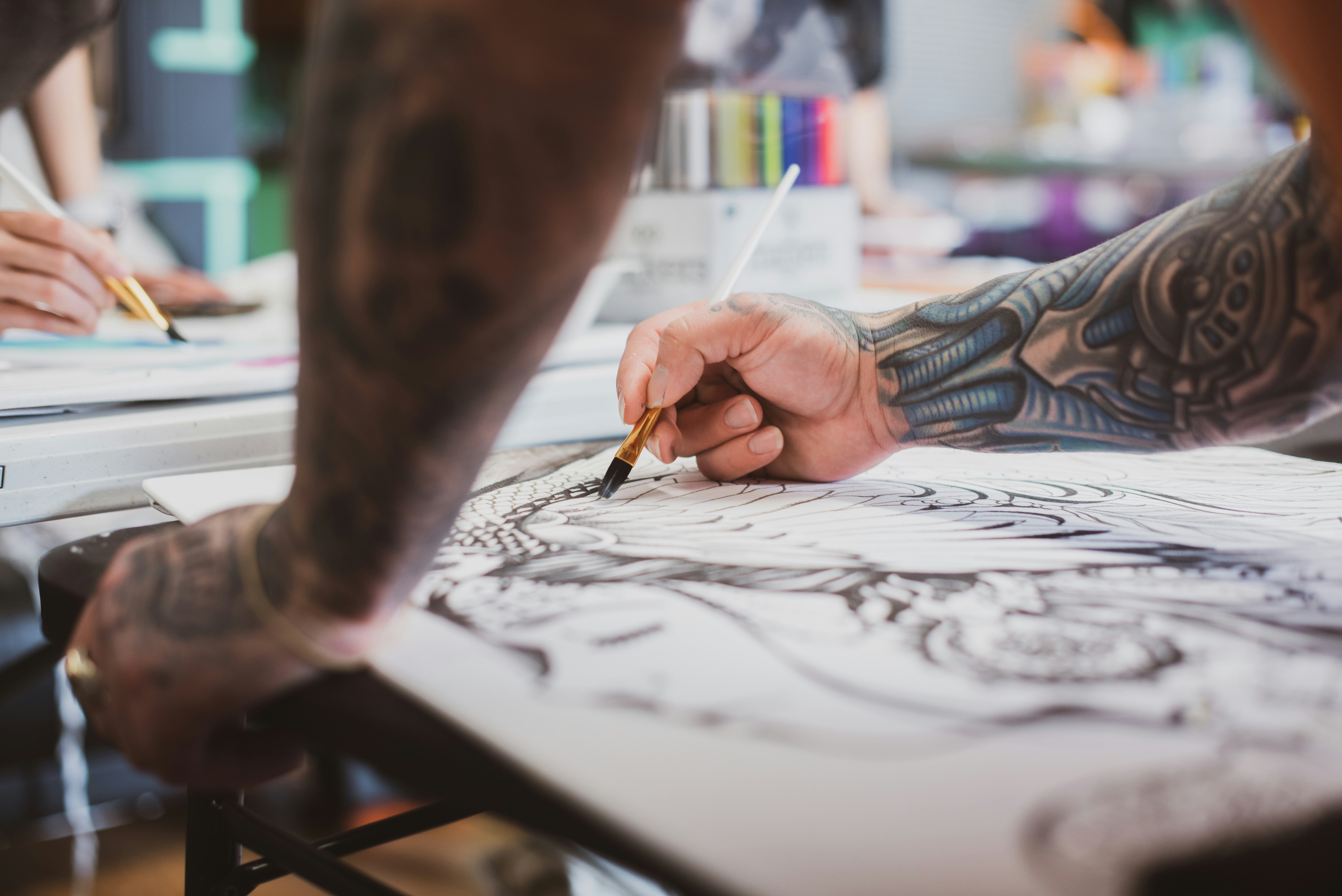 Tattooed artist drawing intricate artwork with a paintbrush