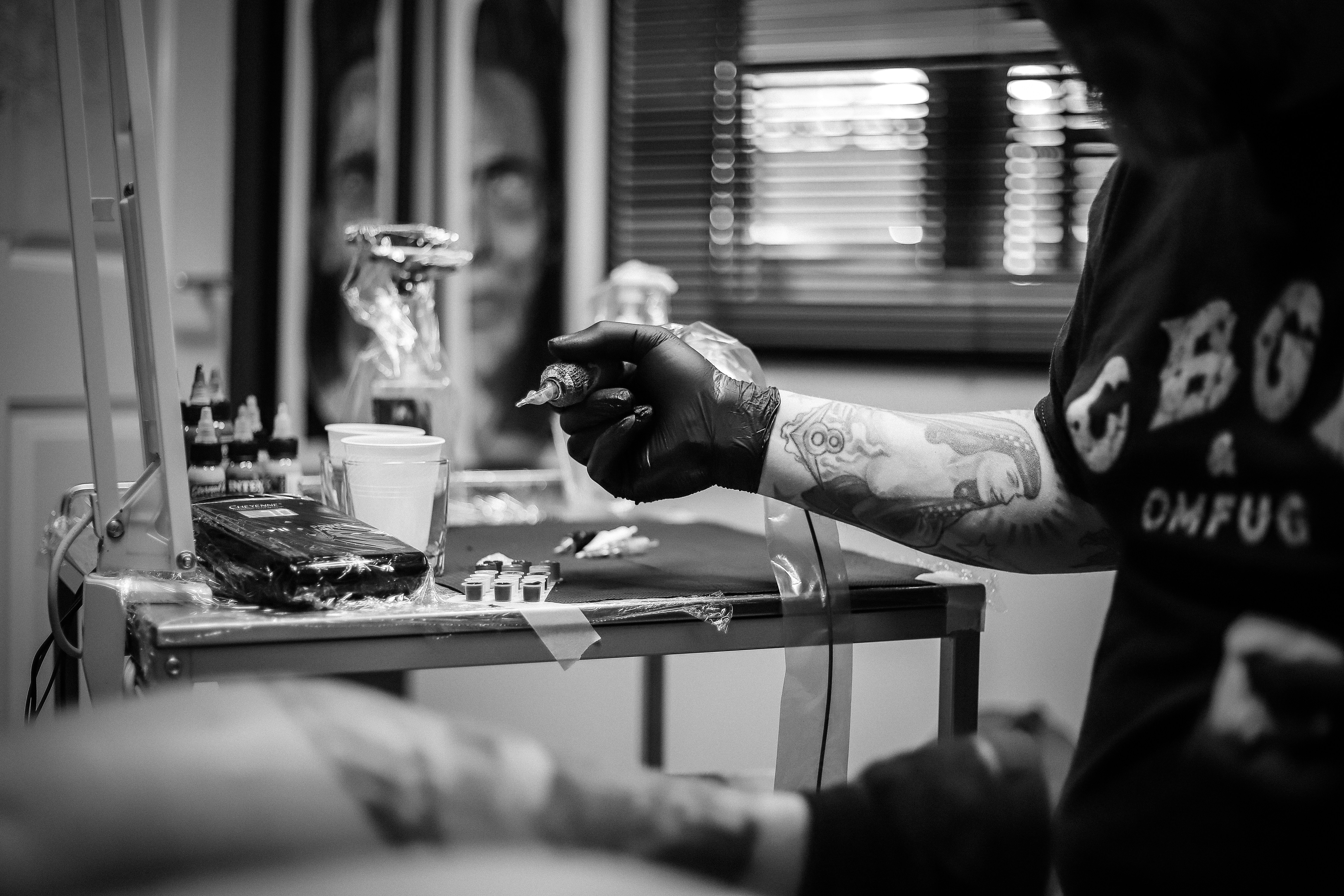 Tattooed artist at their workstation preparing tattoo equipment for a session